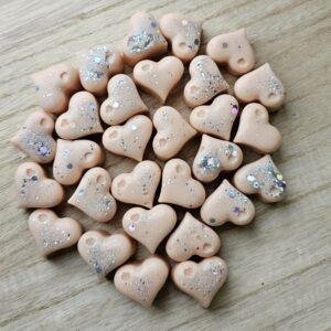 Ročno vliti srčki iz dišečega voska, fotografirani od blizu na mehki, svetli podlagi.